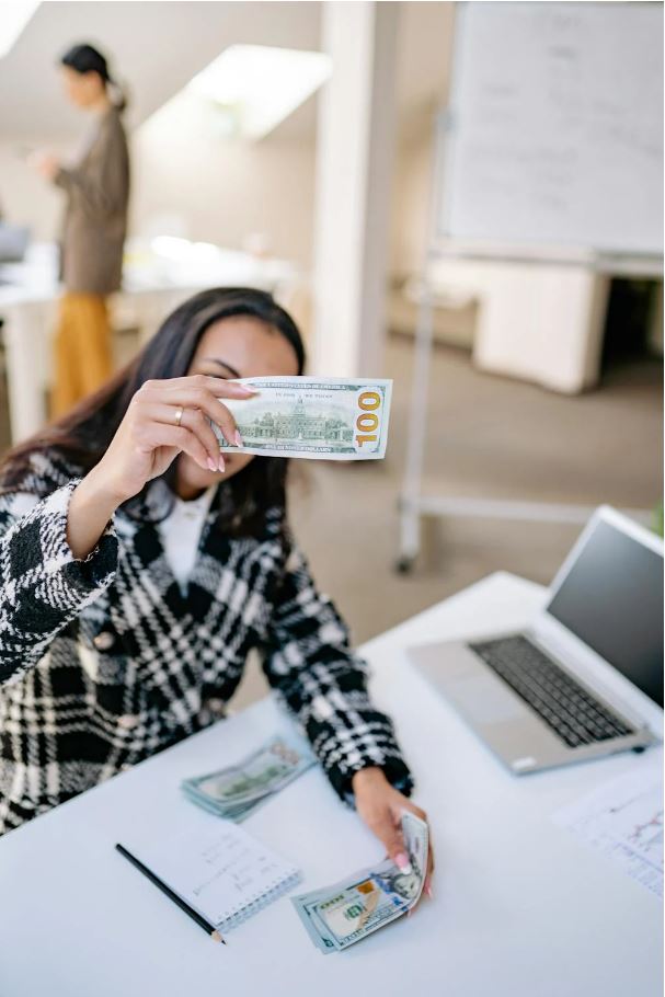 Businesswoman holding a $100 bill and thinking about applying for a working capital loans.